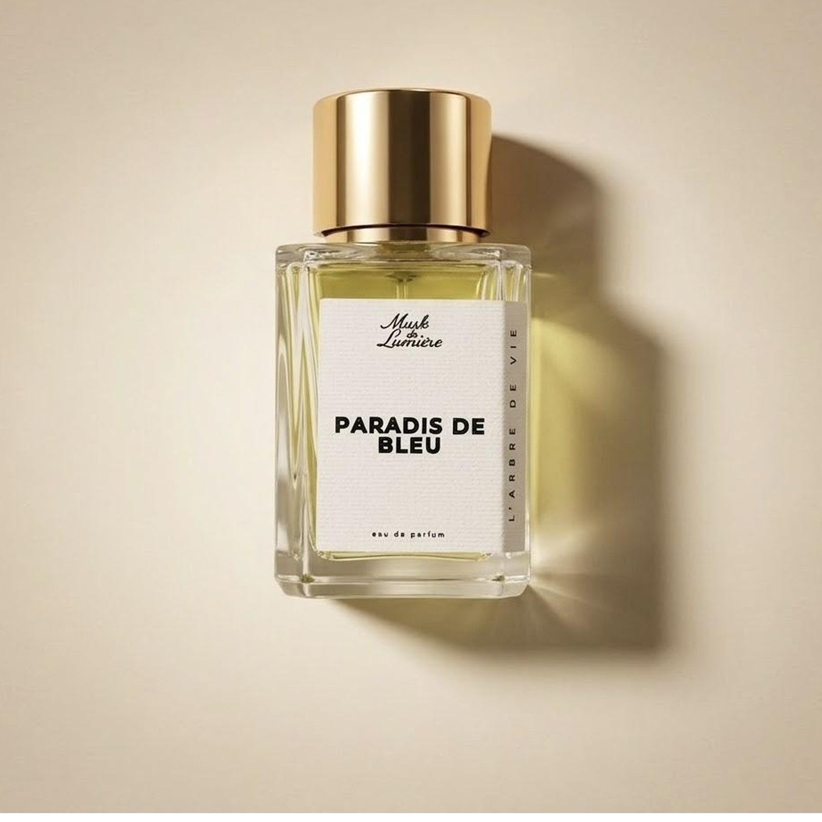 A Musk de Lumière eau de parfum bottle with gold cap resting in warm light