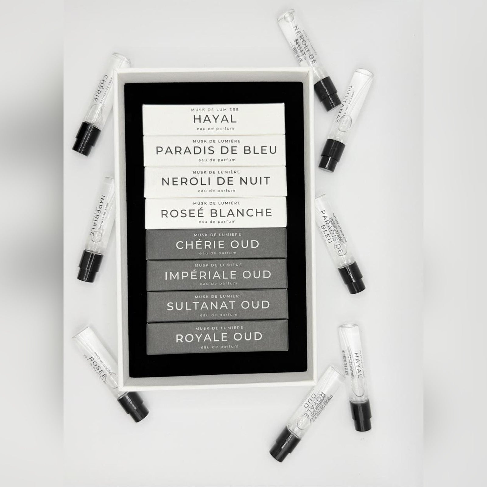 The eight coffrets of the L'Arbre de Vie Discovery Set arranged from white to black with sample vials
