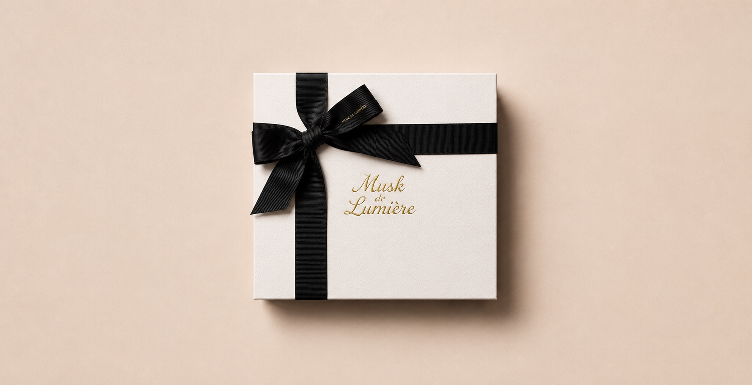 Musk de Lumière signature white gift box with black ribbon and gold script — the gifting experience