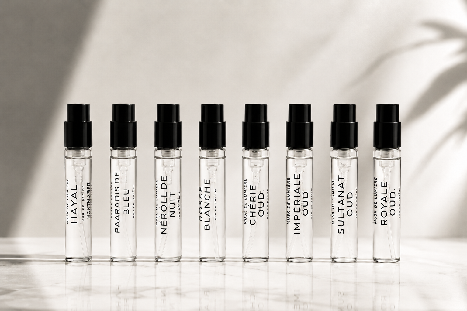 The eight 2.5 ml sample vials of L'Arbre de Vie lined on marble — Hayal to Royale Oud — Musk de Lumière